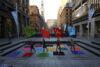 Four people waving colourful flags in the street