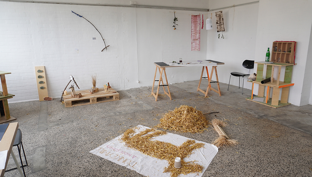 An art installation in a grey room created with composting equipment including woodchips on a table