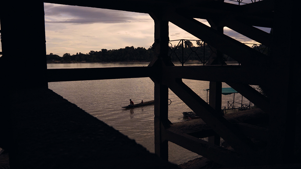 Silhoutte of a boat on the water between the pillars of a building.