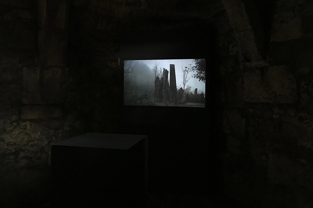 A dark room with a screen showing stone sculptures.