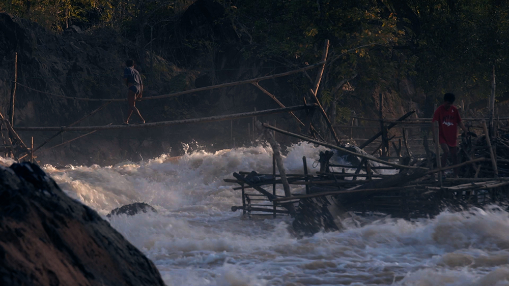 A makeshift bridge over a raging river.