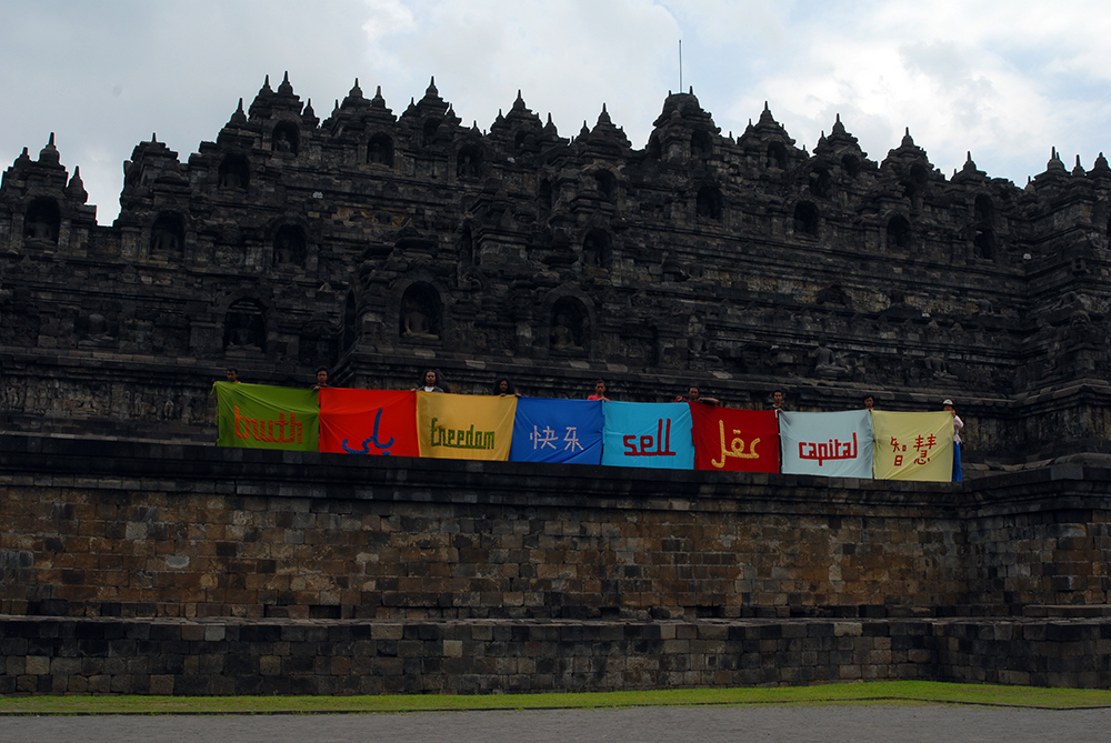 8 flags held on the side of a temple by participants with words in different languages.