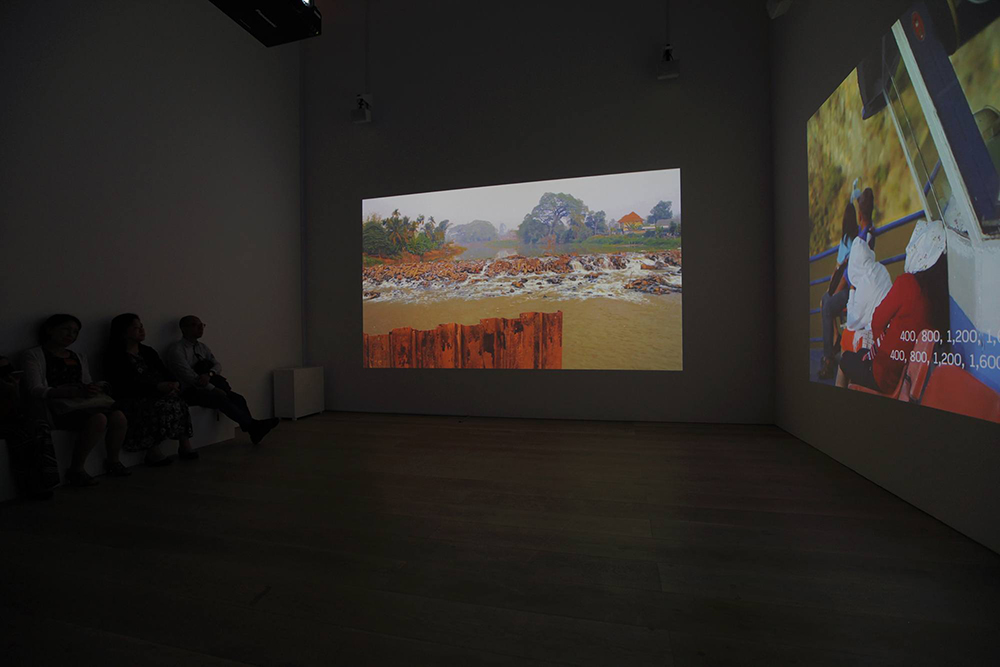 Two videos projected on two walls in a dark room.