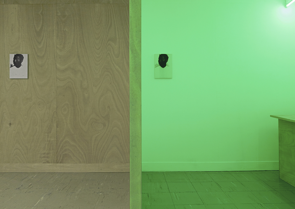 A room split in half, the right side is green and the other brown. An image of a man hangs on both sides of the wall.