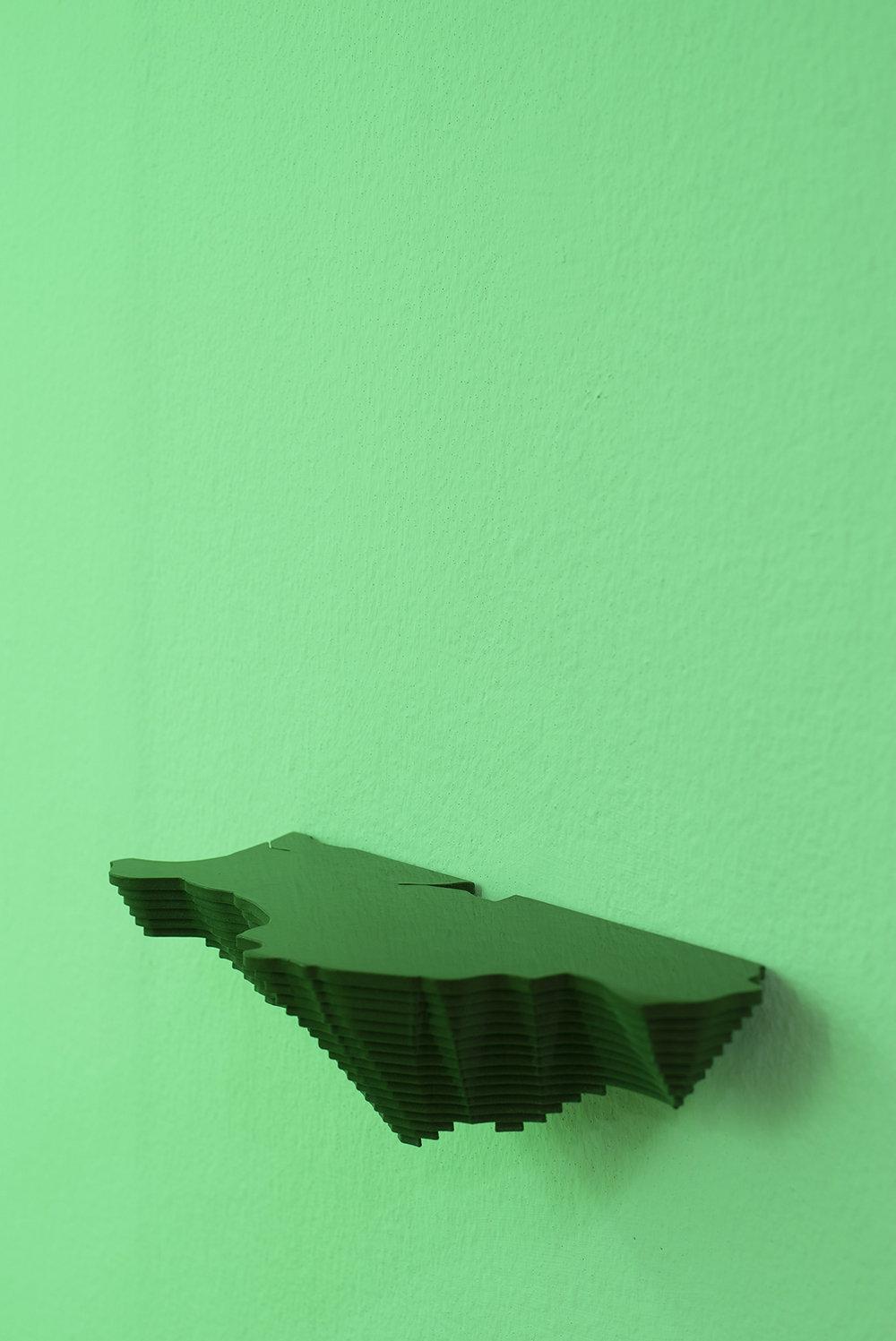 A sculpture of an island hangs on the wall.