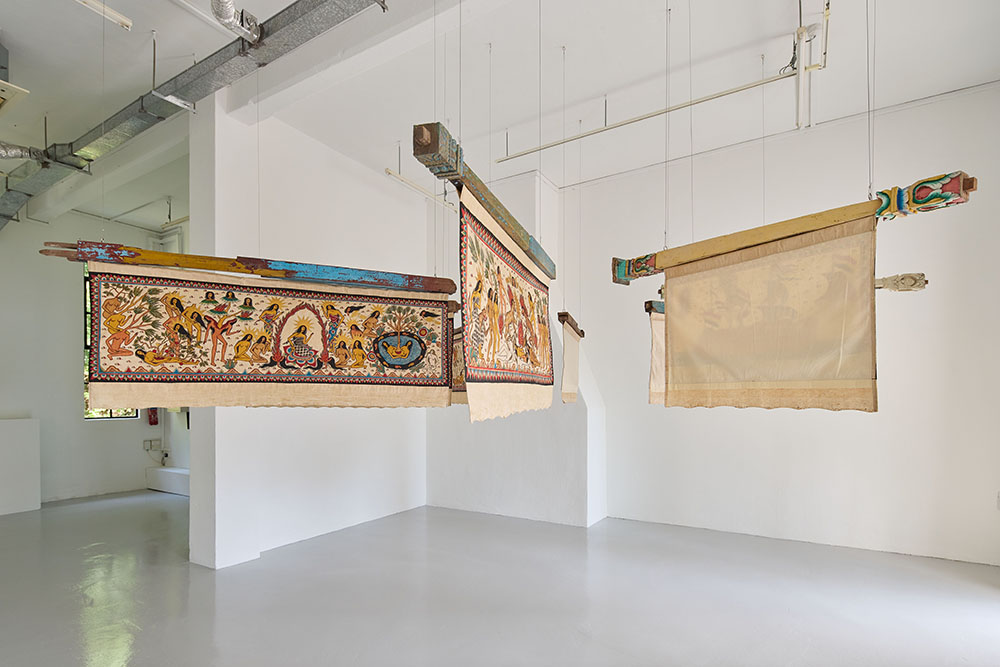 Banners with women on them suspended on wooden beams.