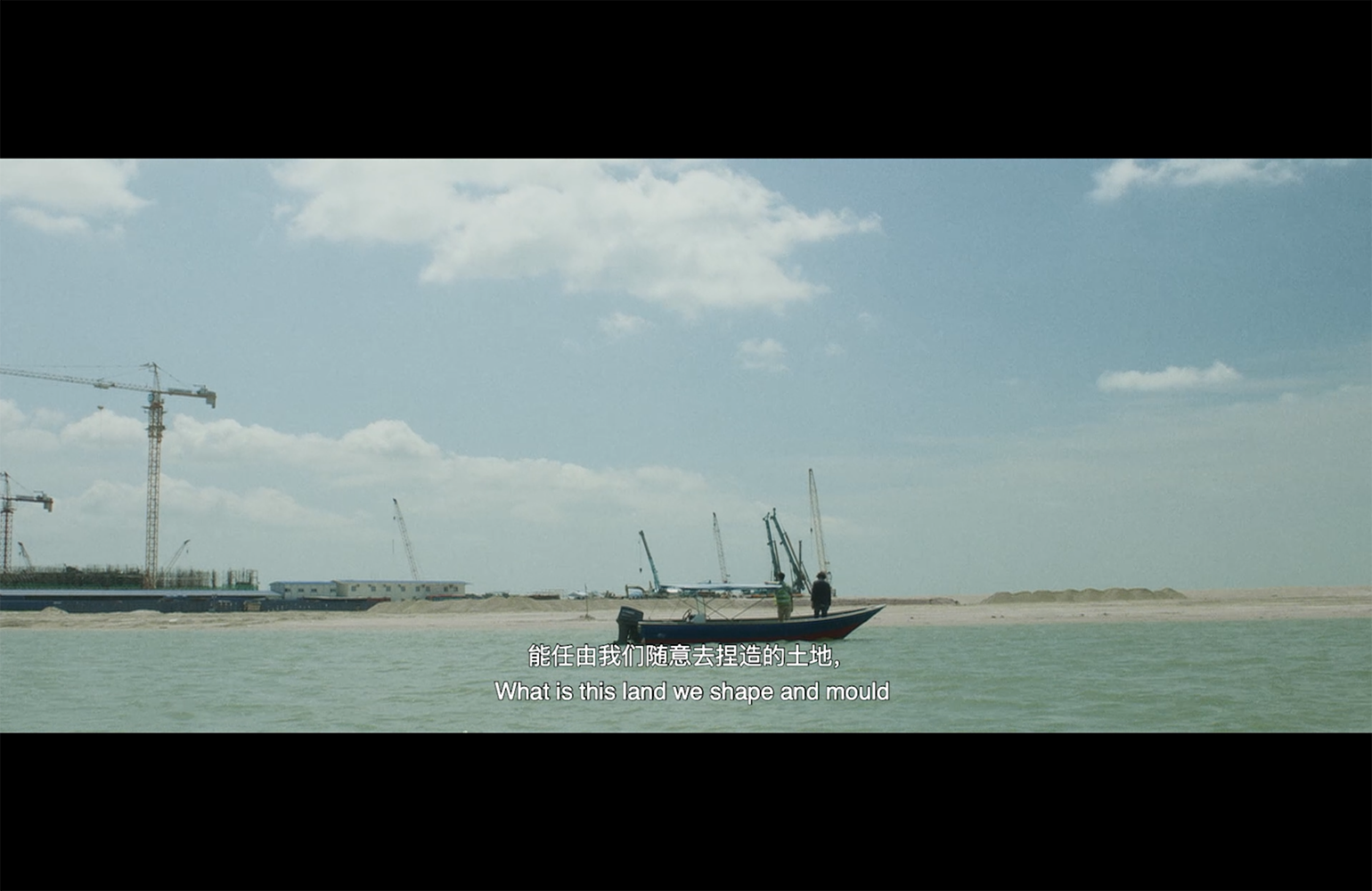 Two people on a boat looking at land being reclaimed with the caption 'What is this land we shape and mould'.